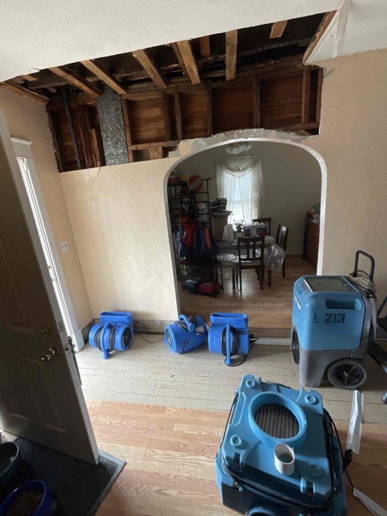 Air movers and a dehumidifier drying a room with the ceiling opened to the joists