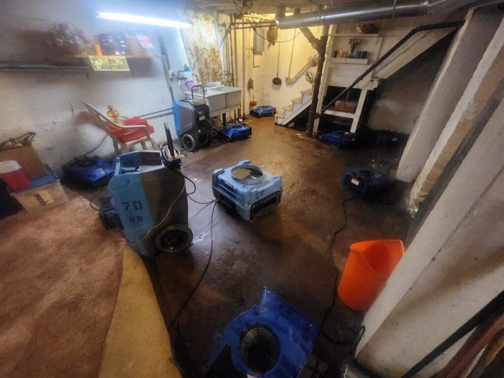 Dehumidifiers and air movers drying a basement after a sewage backup in Muskegon, Michigan