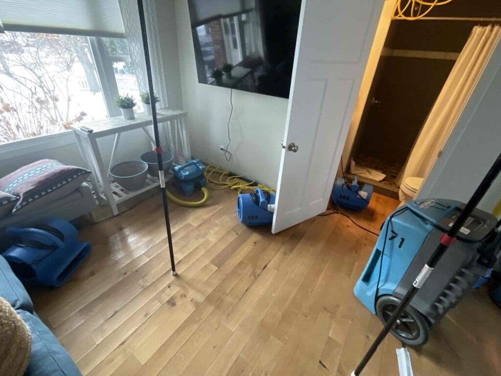 Air movers and a dehumidifier drying a living room after a dishwasher overflow
