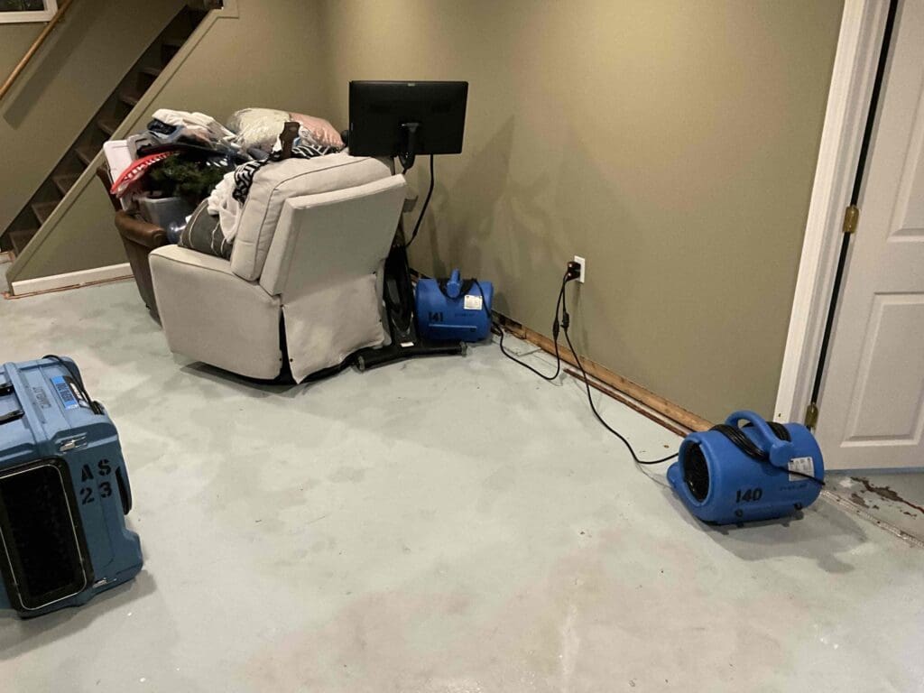 A dehumidifier and an air mover drying a basement after a sewage backup in Grand Rapids, Michigan